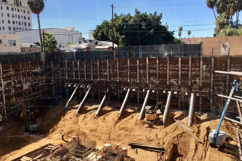 Real excavation project photo showing raker bracing, soldier pile shoring, walers, and temporary support constraints